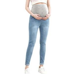 Detail of high-waisted maternity jeans with grey elastic support band in light blue denim