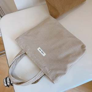 Beige corduroy tote bag with simple wish label shown from top view on white background