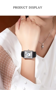 Close-up of rectangular quartz watch with blue hands and black leather strap on wrist