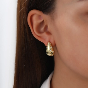 Close-up of 18k gold-plated teardrop earrings with heart pattern and sparkling crystals