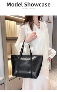 Fashionable black oil wax leather tote bag shown on model in a cozy indoor setting