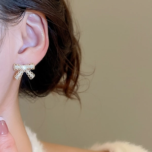 Close-up of gold bow earrings with micro-pave zircons and center square stone on model
