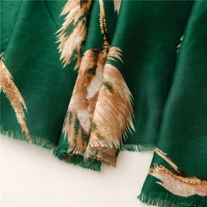Close-up of dark green scarf showing gold foil feather prints and frayed fringe edges
