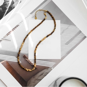 Vintage beaded tiger eye stone necklace with golden accents on a minimalist background