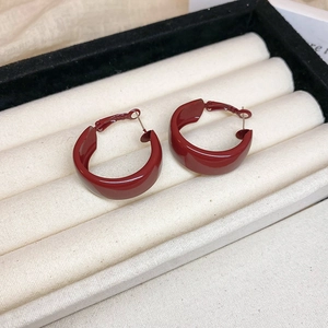 Detail view of deep red round hoop earrings on beige velvet inside a black jewelry box