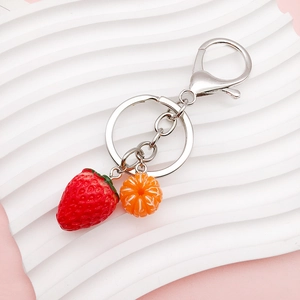 Close-up of acrylic strawberry and orange fruit charms on a silver metal keychain