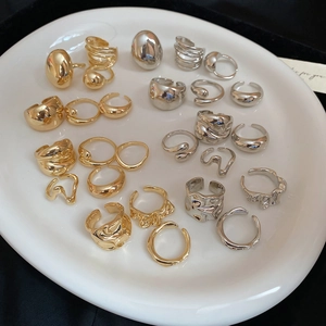 Detailed display of irregular textured gold and silver open rings on a ceramic tray