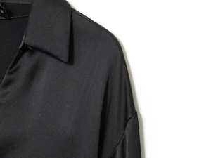 Dettaglio camicia di raso nero con trama liscia, colletto e cucitura della spalla