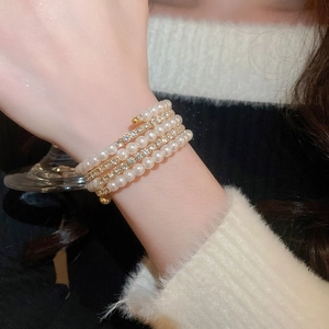 Detail of multilayer pearl and rhinestone wrap bracelet on wrist with elegant knit background