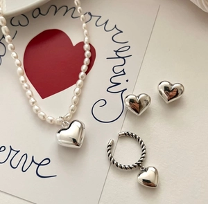 Detailed set of pearl necklace and 3D heart-shaped silver earrings on a romantic card