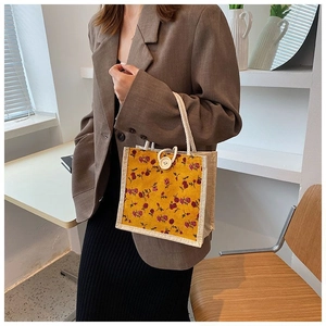 Detailed side view of floral mustard yellow tote bag held by model in minimalist room
