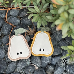 Detail of pear-shaped mini bags with leaf accents and fine stitching on pebbles