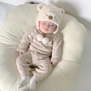 Dettaglio del set neonato in maglia beige con cappello a forma di orso e calzini bianchi