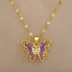Detailed shot of golden butterfly pendant with purple gemstones on a thin titanium steel chain