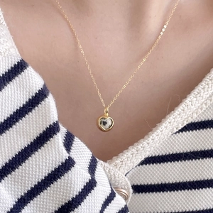 Close-up of a heart-shaped zebra stone pendant necklace worn by a model on a gold chain