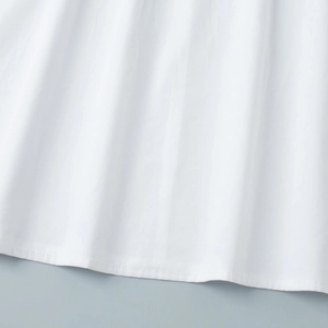 Detail view of the white cotton fabric hem showing uniform stitching and fine texture