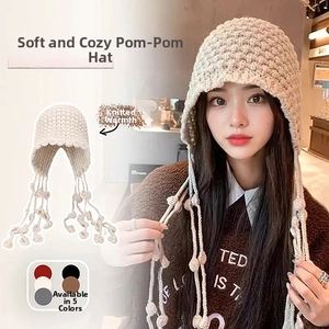 Detailed view of plush knit bucket hat with soft fur texture and hanging pompom charms