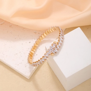 Elegant gold wrap bracelet featuring sparkling oval zircons on white geometric display