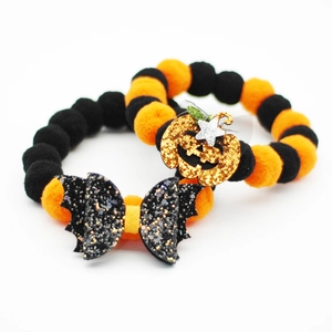 Detail of Halloween pet collar featuring plush orange and black balls with glitter pumpkin charm