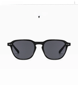 Detailed close-up of bright black square sunglasses with gray lenses on a white background