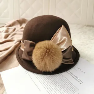 Elegant wool cloche hat in coffee brown with satin bow and pompom on vintage magazine