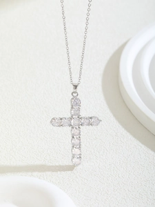 Close-up of silver cross pendant with sparkling cubic zirconia on a fine steel chain
