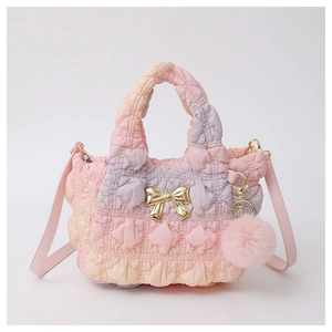 Detail of gradient cloud bag showing quilted texture, gold bow, and plush pompom charm