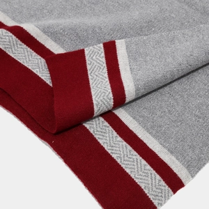 Macro detail of grey knit scarf with herringbone pattern and red white striped edge