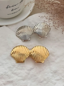 Détail de barrettes coquillages élégantes en or et argent sur un fond texturé