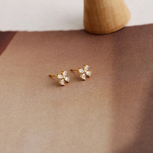 Macro view of gold-plated flower stud earrings featuring pear-cut clear zircon petals