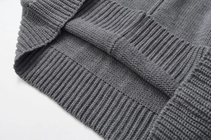 Detailed close-up of dark grey thick knit sweater featuring ribbed hem and coarse texture