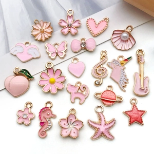 Detailed flat lay of pink enamel charms featuring golden hearts, unicorns and butterflies