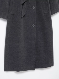 Detailed texture of dark grey wool coat featuring mid-section cut and matching belt