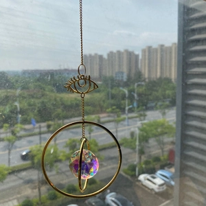 Golden suncatcher with eye-shaped metal frame and multifaceted crystal ball window prism