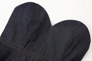 Primer plano del top de mezclilla azul oscuro con costuras en contraste naranja y textura
