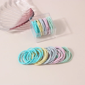 Detailed macro of colorful spiral hair ties in a clear storage box with soft lighting