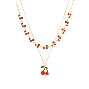 Collier double épaisseur doré en acier inoxydable avec pendentifs cerises rouges sur fond blanc
