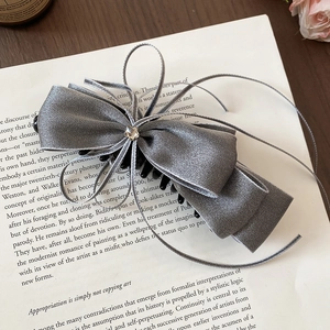 Detailed view of a grey silk bow hair claw clip with rhinestones and flowing tassels
