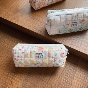Detailed view of quilted floral fabric pouches with zipper and woven BEST label tags