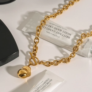 Elegante collana in acciaio al titanio dorato con chiusura OT e ciondolo a sfera irregolare