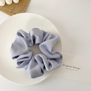 Minimalist satin silk scrunchie in light blue and lilac purple on a white tray