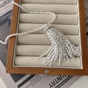Elegant pearl necklace with wheat ear tassel pendant displayed in a wooden jewelry box