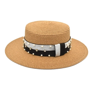 Close-up of straw boater hat featuring black ribbon with white pearls and rhinestones