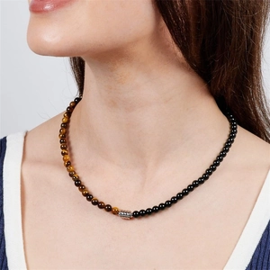 Close-up of 6mm natural tiger eye and black obsidian beaded necklace worn by a model