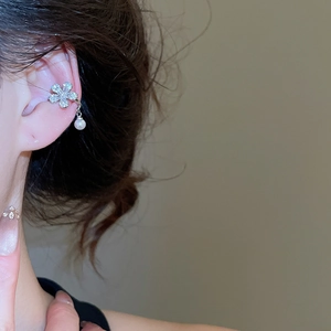 Close-up of zircon five-petal flower ear cuff with a hanging white pearl on model