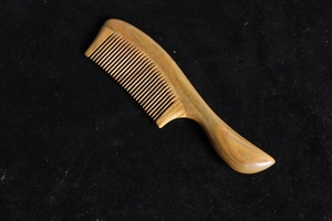 Detailed close-up of natural green sandalwood comb with fine teeth and thick round handle