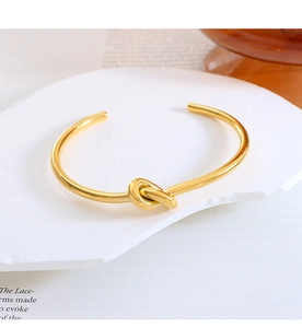 Detailed view of gold knotted cuff bracelet featuring a minimalist sleek knot design
