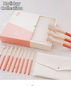 Detail of 12-piece makeup brush set with coral handles and cream storage bag in gift box