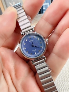 Detail of silver quartz watch with blue dial and rhinestone indices held by hand