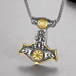 Detailed view of silver Viking Mjolnir pendant with gold compass and wolf head reliefs
